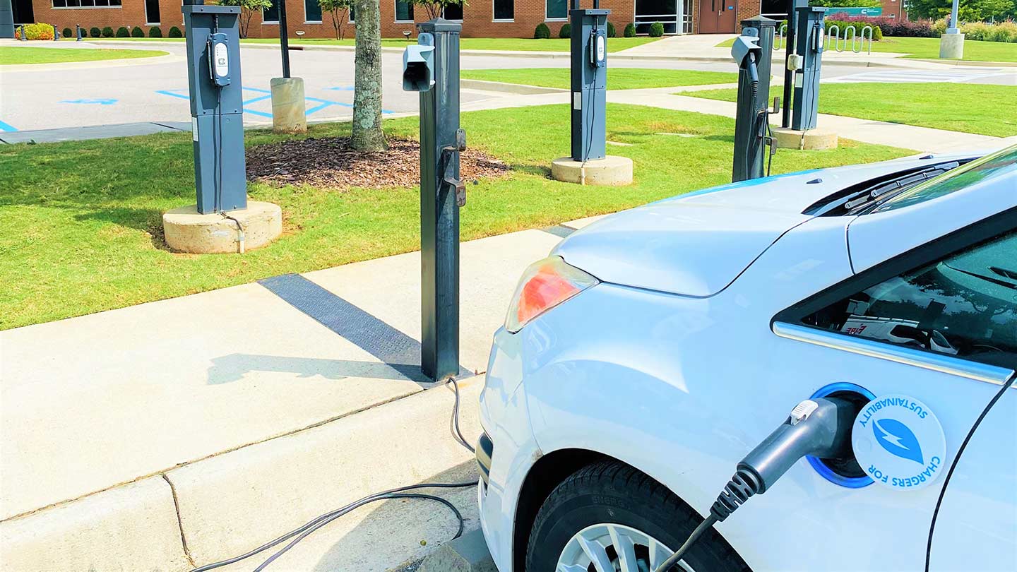 electric car parked in lot and plugged into charging station.