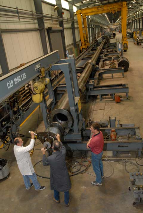 People assembling a long metallic tube