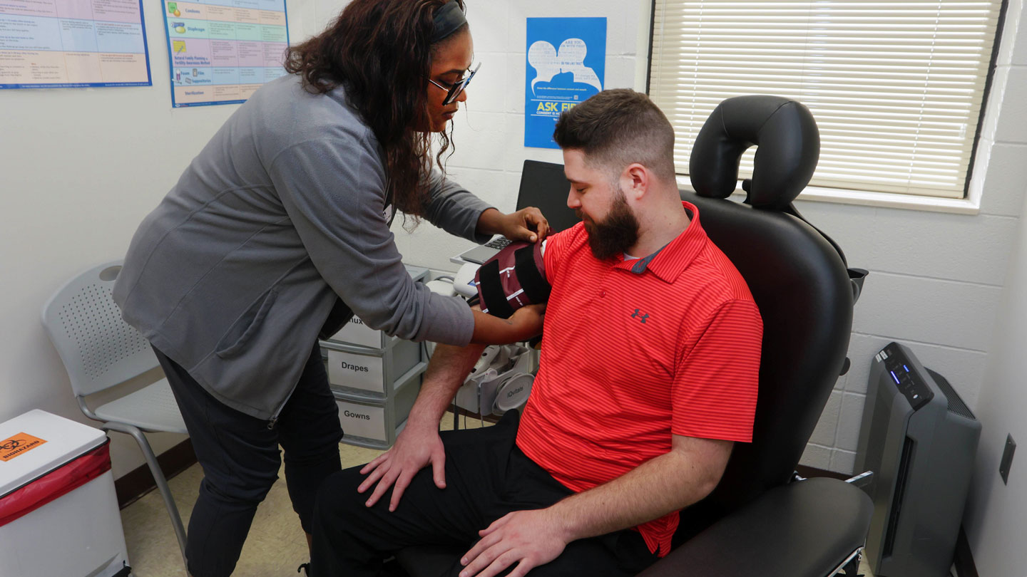 an employee gets his blood pressure measured by a clinic staff member