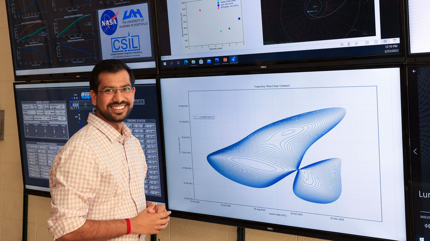 A UAH graduate students pauses and smiles during a multi-screen presentation of his aerospace research.