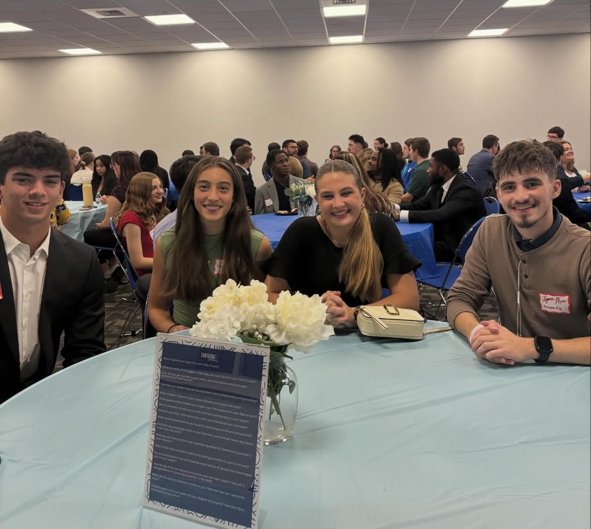 Four emerging leader participants smiling at camera while sitting at a table.