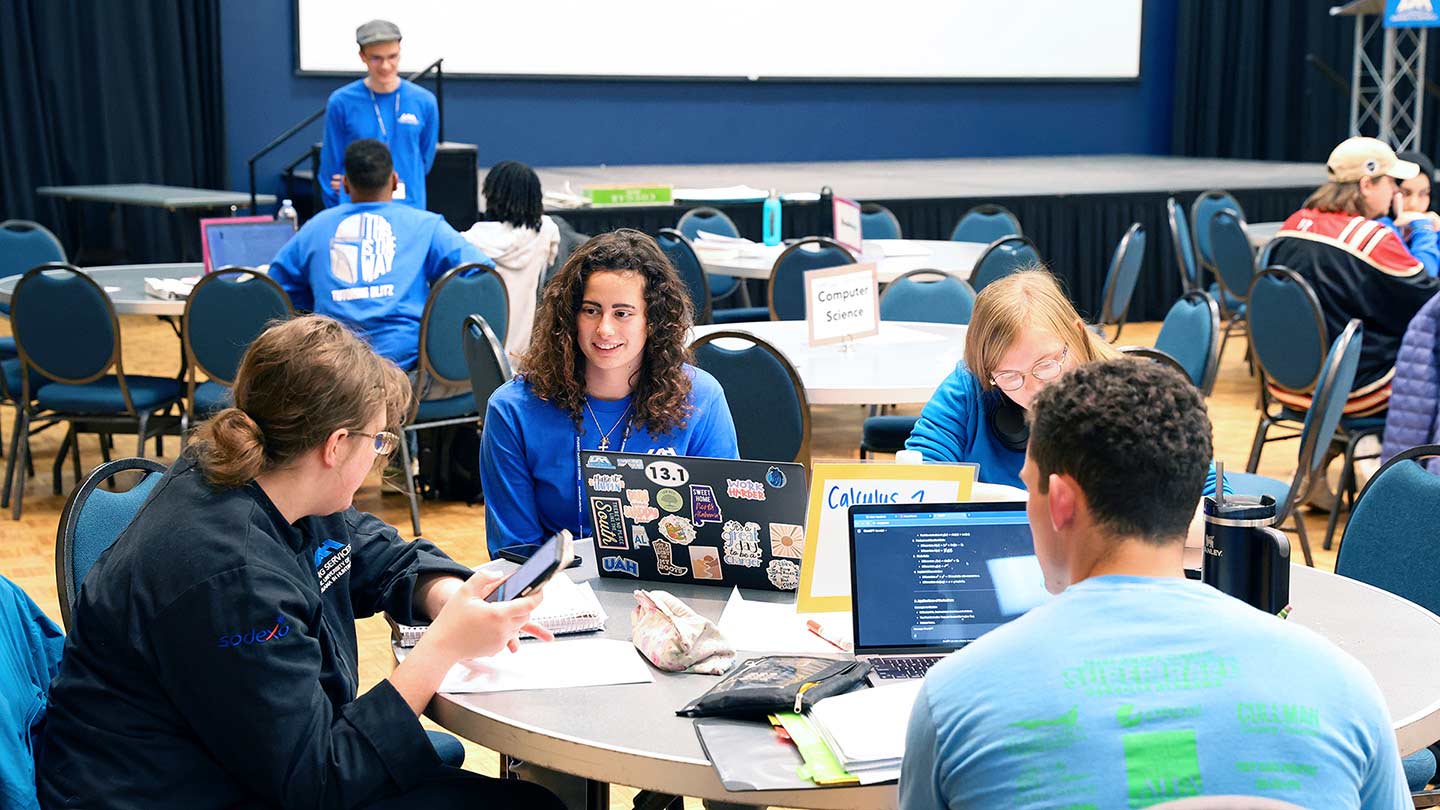 students setting around a table being tutored.