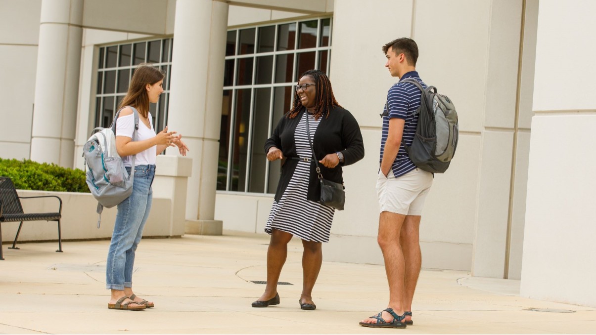 Three U A H graduate students laugh together during a conversation