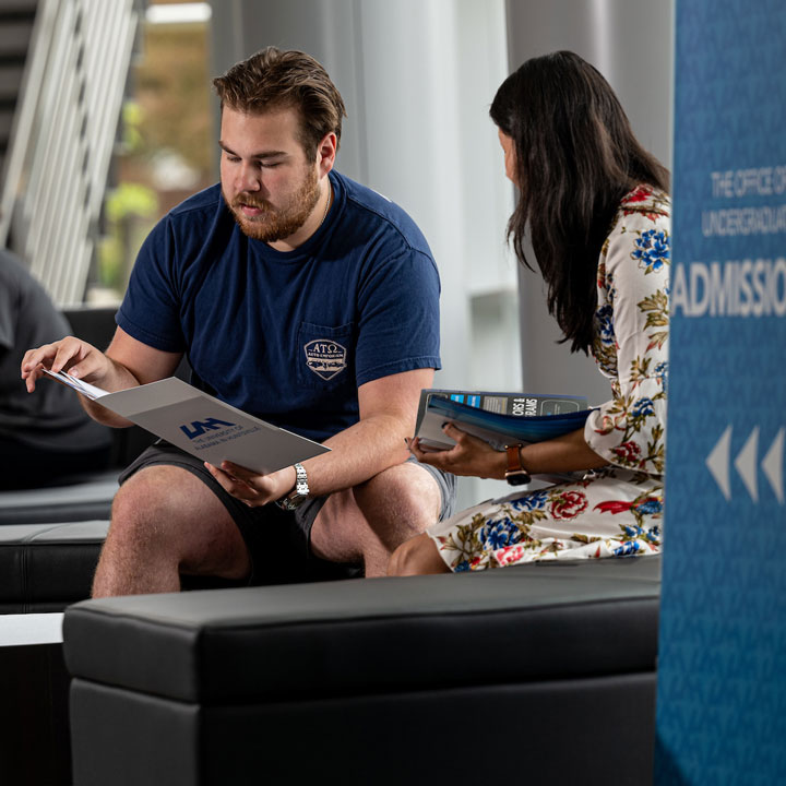 A prospective student reads admission materials with a counselor