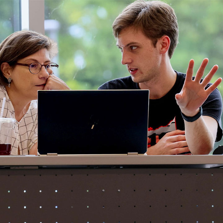 A communications professor thoughtfully reads and critiques a graduate student's writing.
