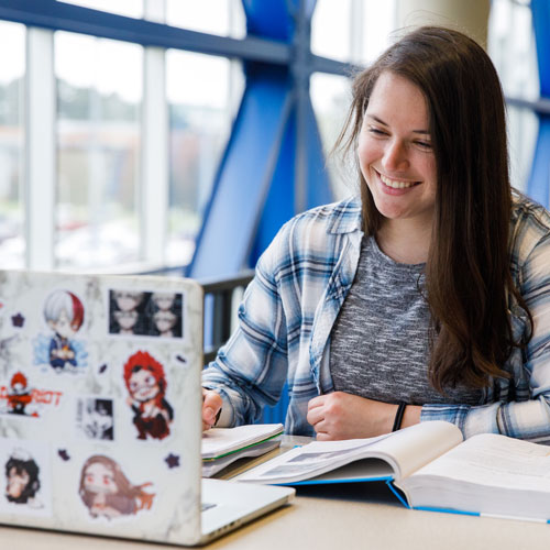 a smiling student works on her laptop