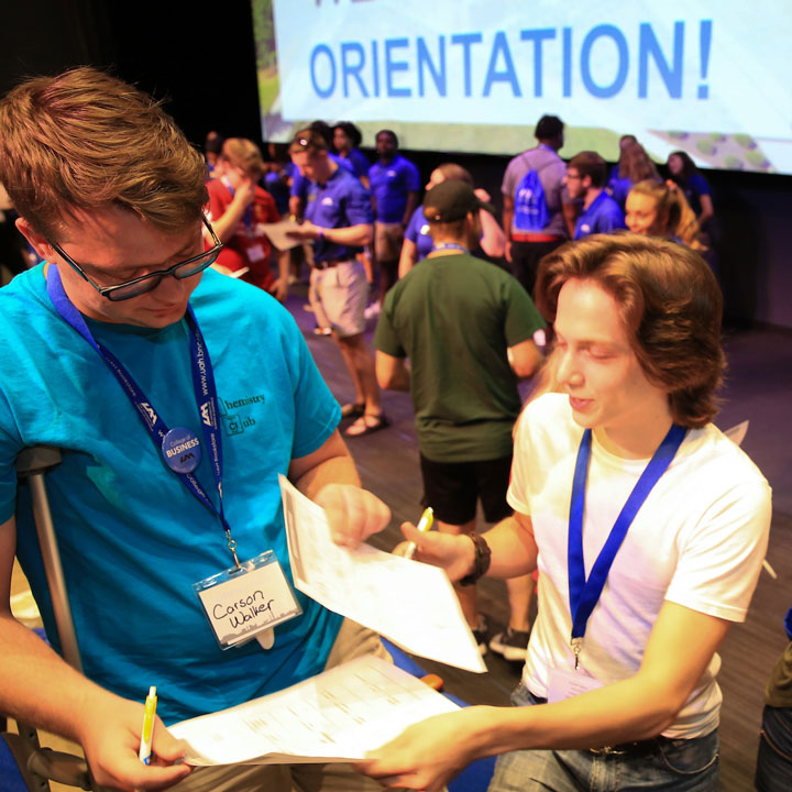 A student volunteer helps another student at a new student orientation event.