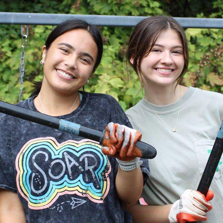 Two smiling U A H student students participate in a community service gardening event.