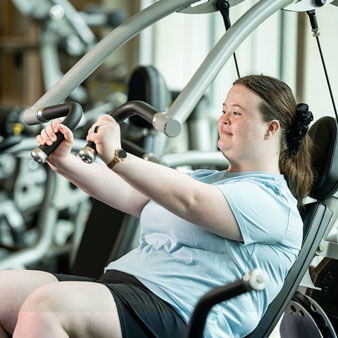 A U A H graduate student uses a weight lifting machine at the University Fitness Center.