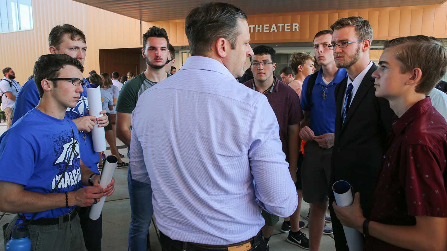 Alumni surrounded by several students, talking to students at an event.