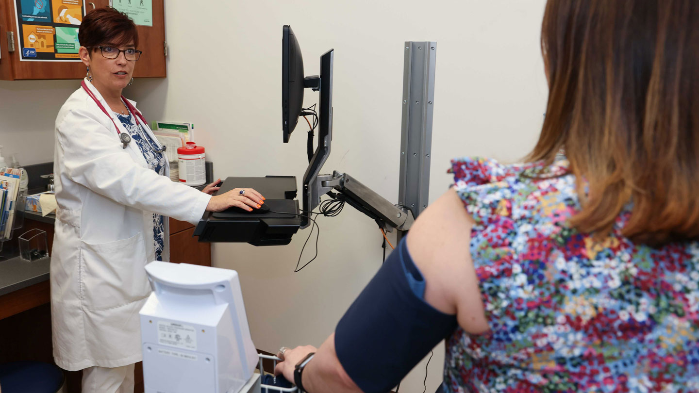 Connie Abbott conducts a heath screening with a patient at the UAH clinic