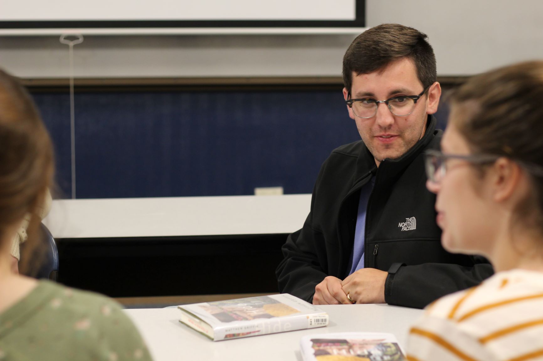 Students setting in a classroom listening to another speak