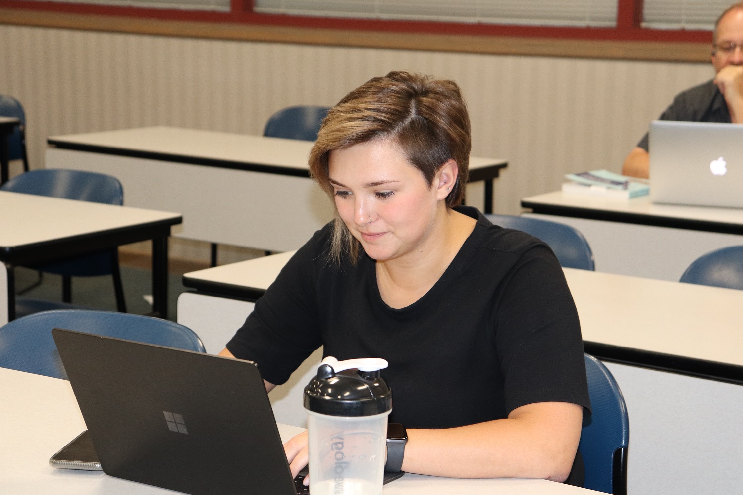Student setting at a desk in grad class with computer.