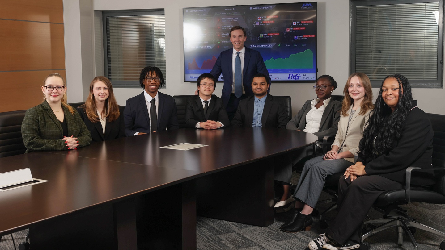 students sitting around desk in business professional starring at camera