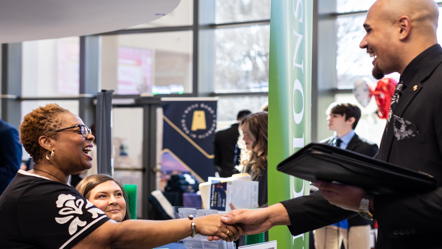 A student shakes an employeers hand at the COB career fair