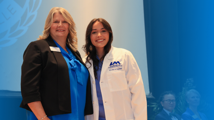 Associate Dean, Dr. Sheila Gentry in a charger blue blouse and blazer, standing to the left of Dual Nursing Student, Elizabeth Wilson in white lab coat style jacket with light blue scrubs