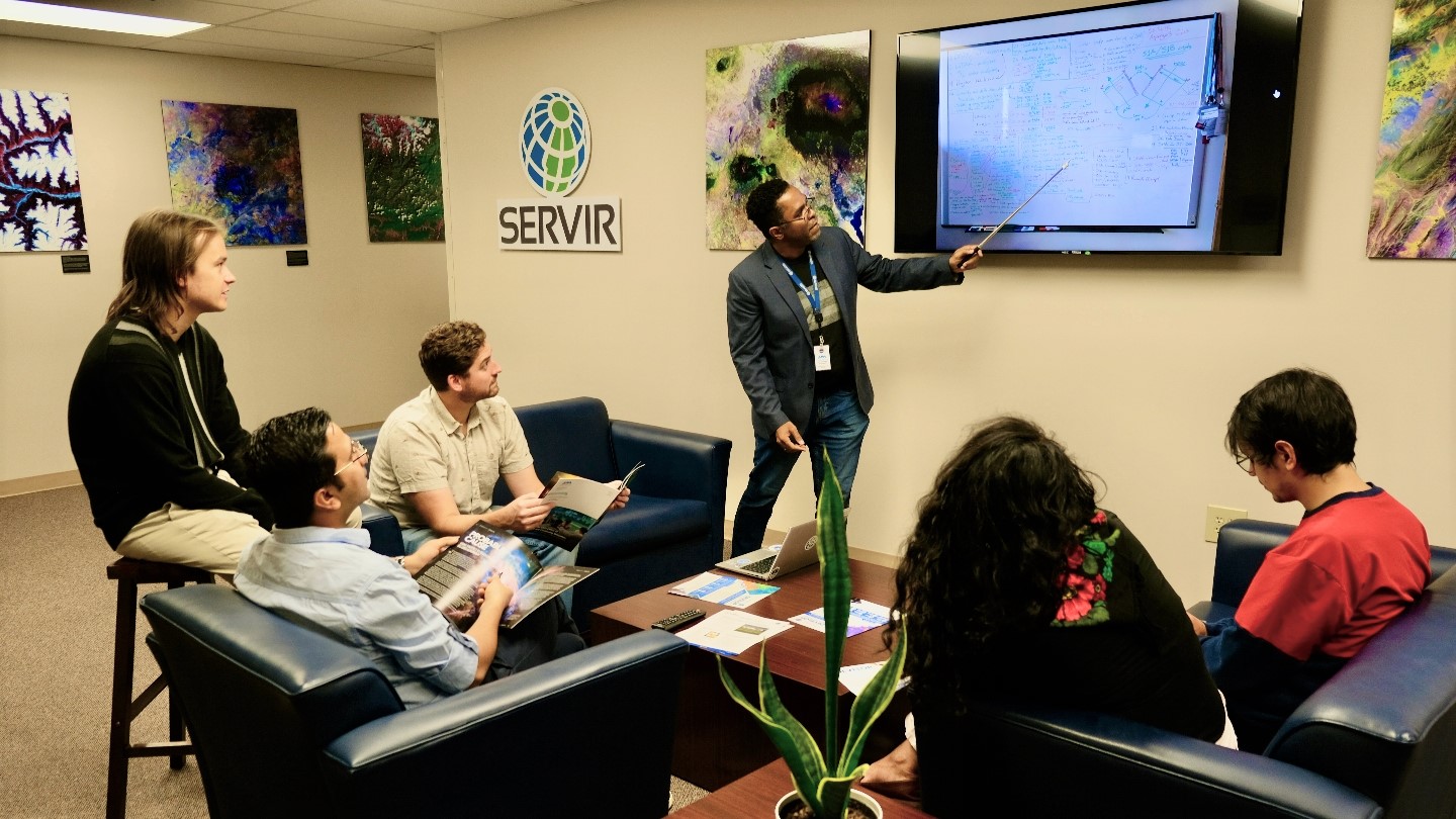 group of people sitting with one person presenting on screen