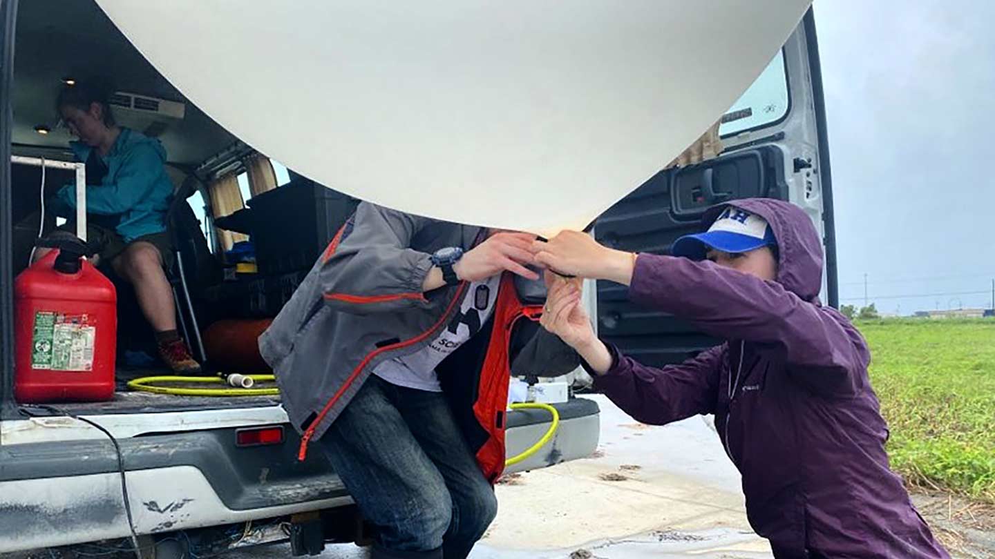 UAH AES students tie off a weather balloon in preparation to launch ahead of Hurricane Ida's outer spiral rain bands.