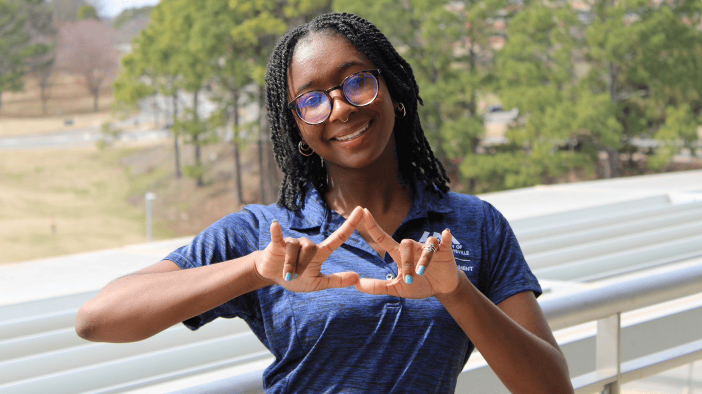 LoriElle Hutchinson, a senior majoring in Computer Science at the University of Alabama in Huntsville (UAH), creates the letters U A H using her hands.