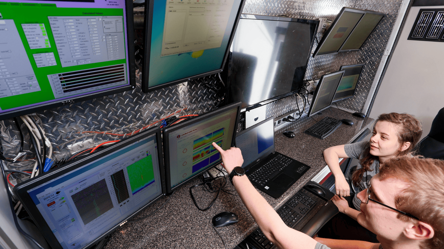 Atmospheric and Earth Science students at UAH (The University of Alabama in Huntsville) studying meteorology analyze weather data on multiple computer monitors inside a mobile weather truck.
