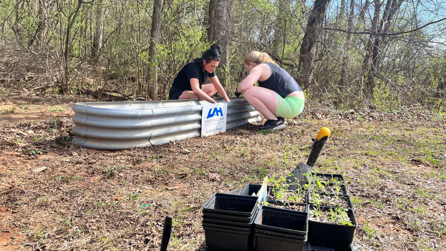 Photo Description: Lara Rae Holladay and Lauren Womack planting monarch butterfly wildflowers and milkweed at green way at Indian Creek, Huntsville, AL