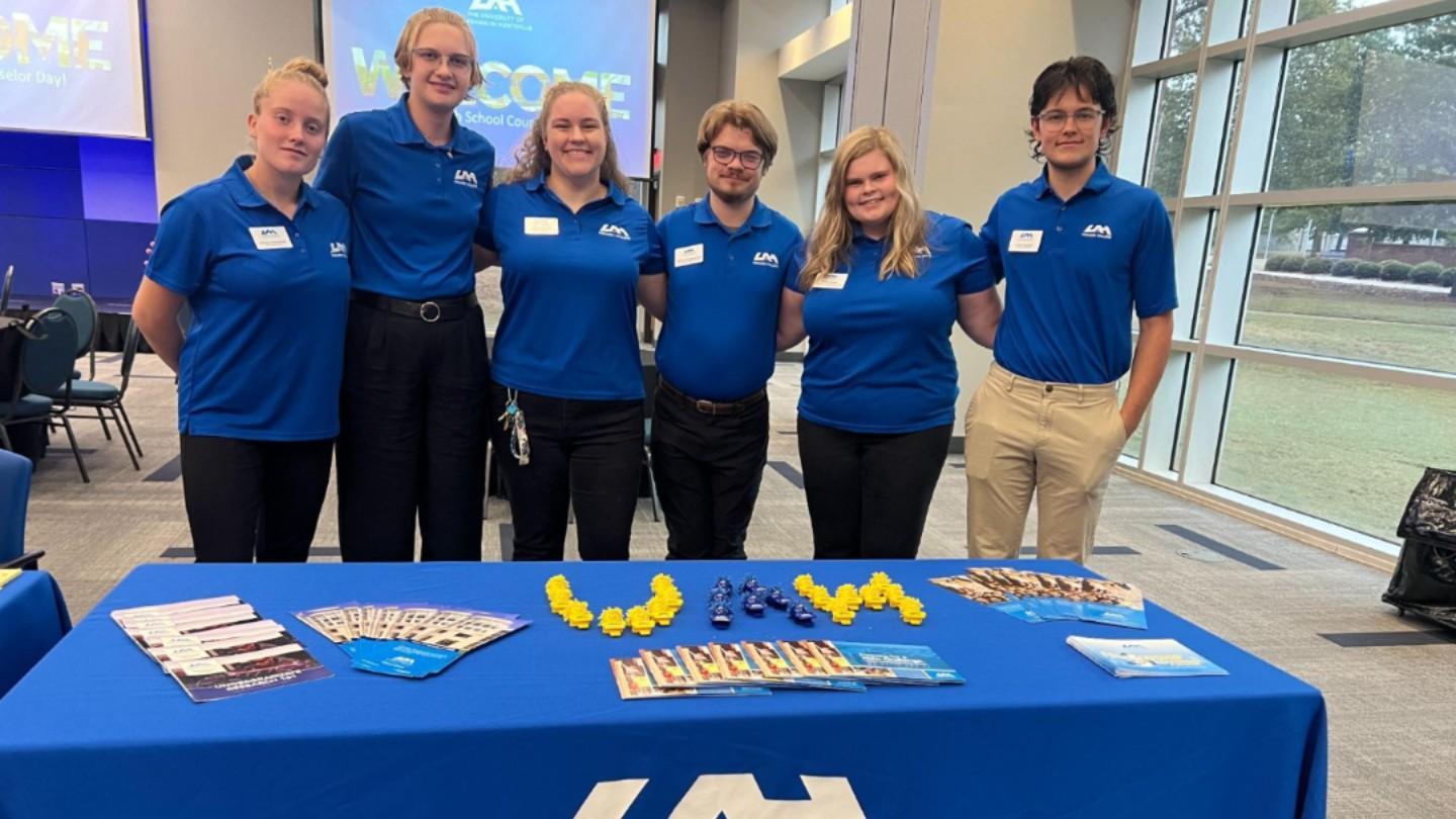 Honors ambassadors behind their table at an event