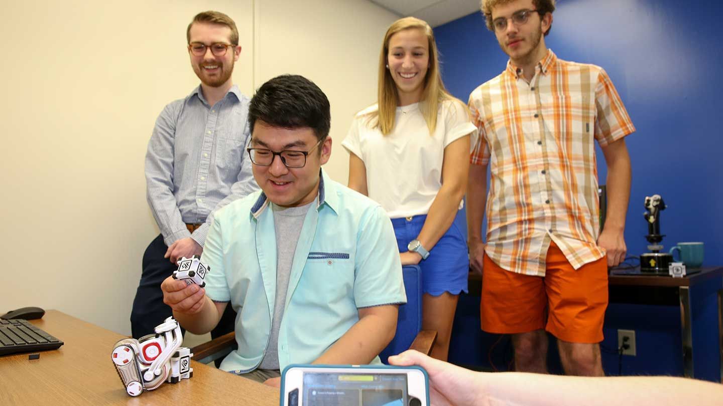 a group examines a small robot and its cube