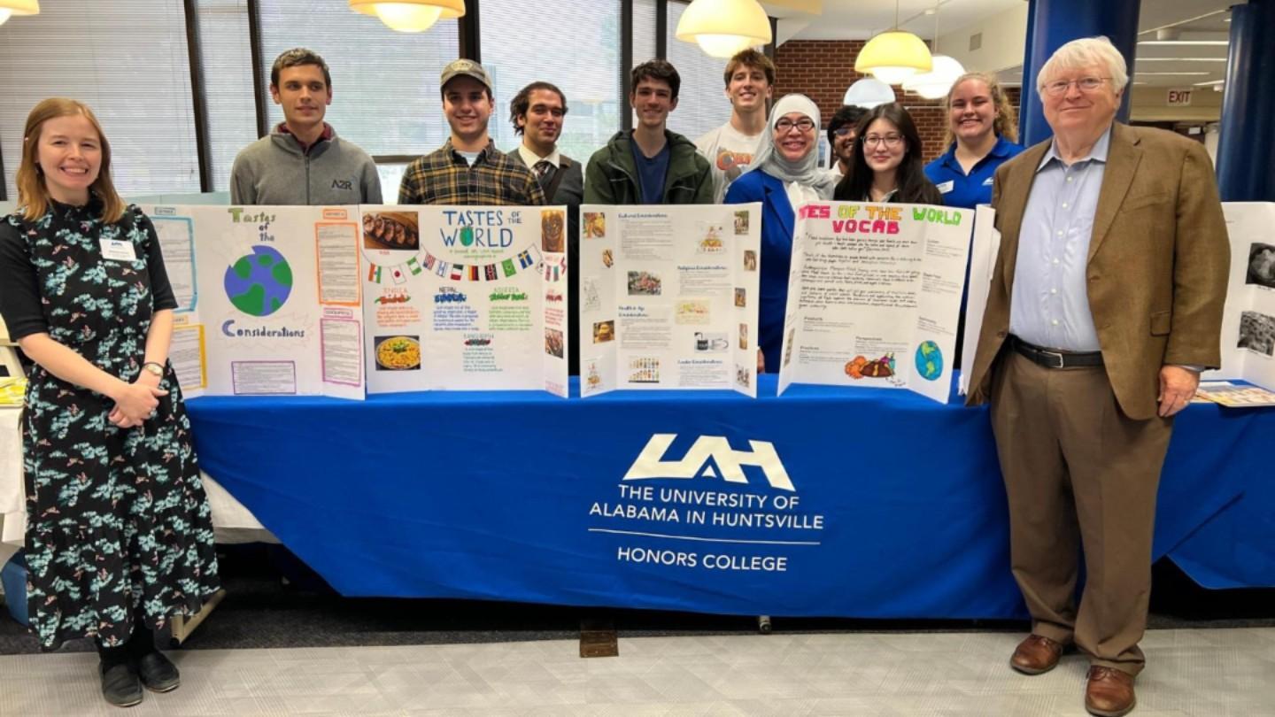 Honors students and some staff smiling around a table with research posters on it