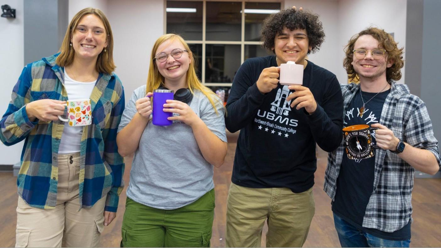 Four students posing with their coffee mugs and smiling