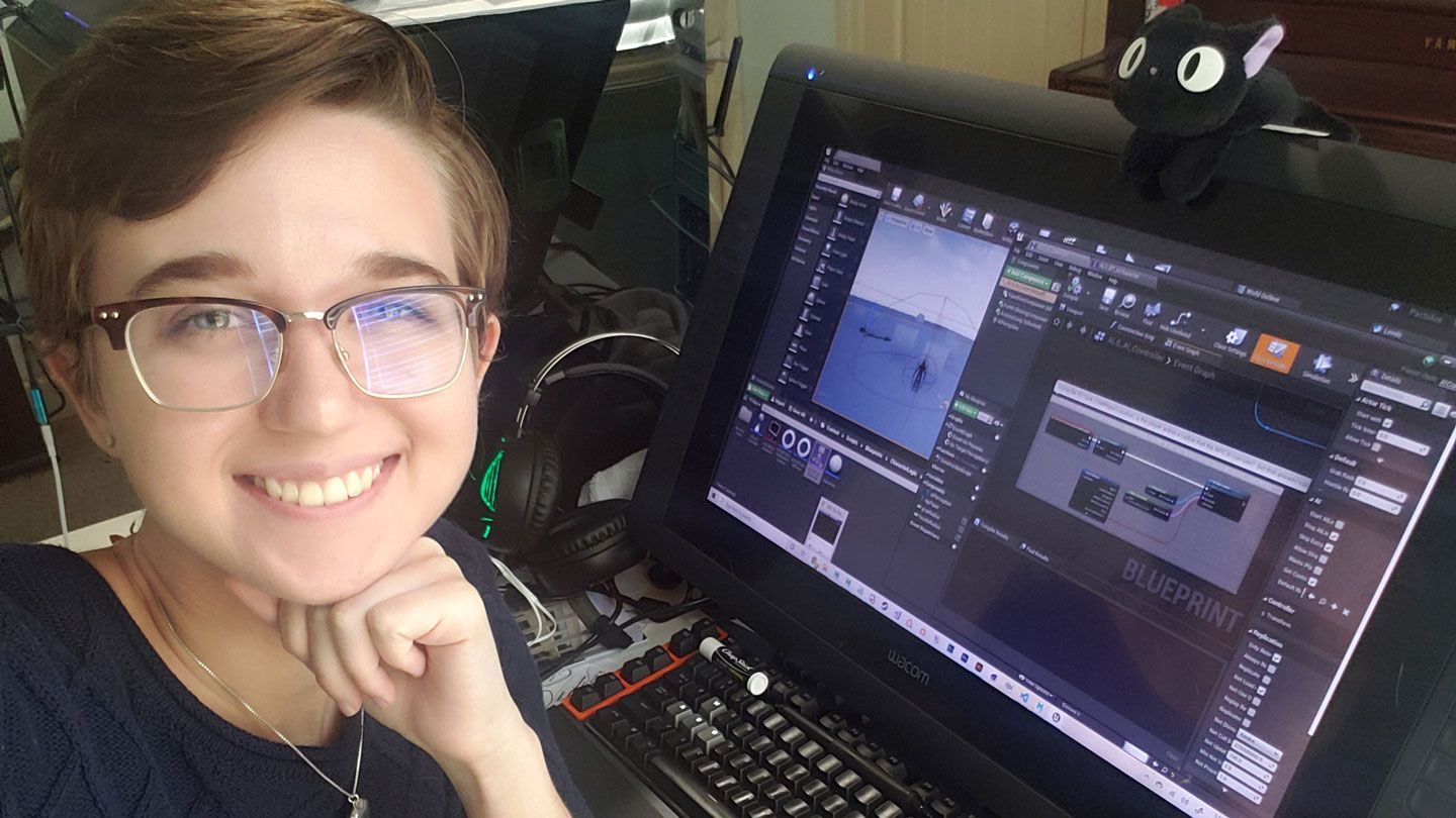 a young woman college student at UAH with short hair and glasses works on a design research project at a desktop computer