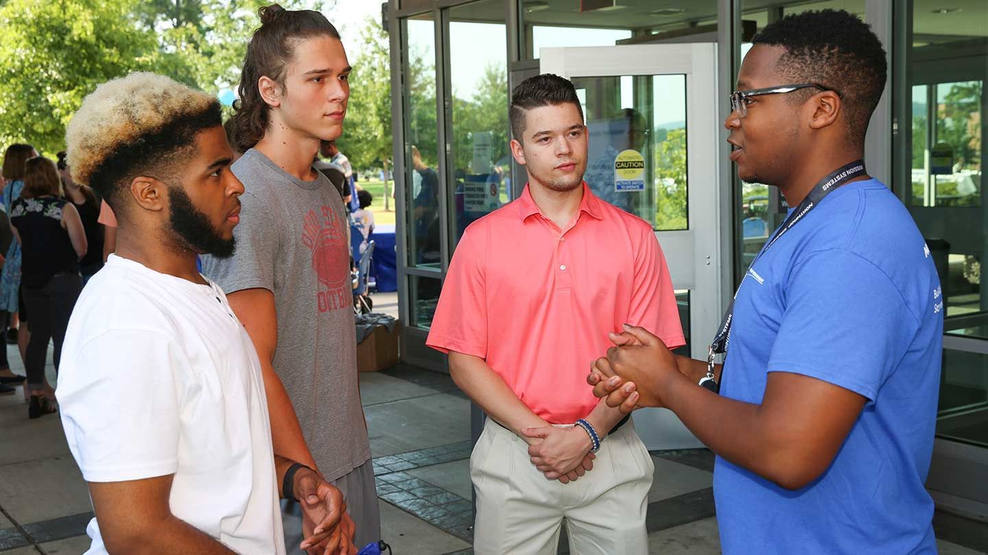 four men stand and talk in a group