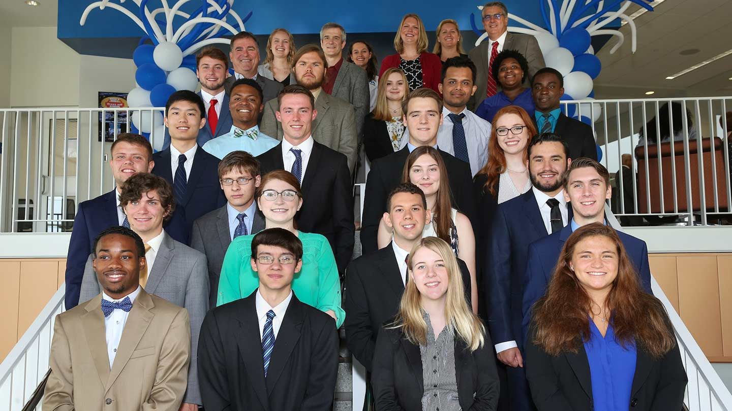 several alumni stand in formal attire