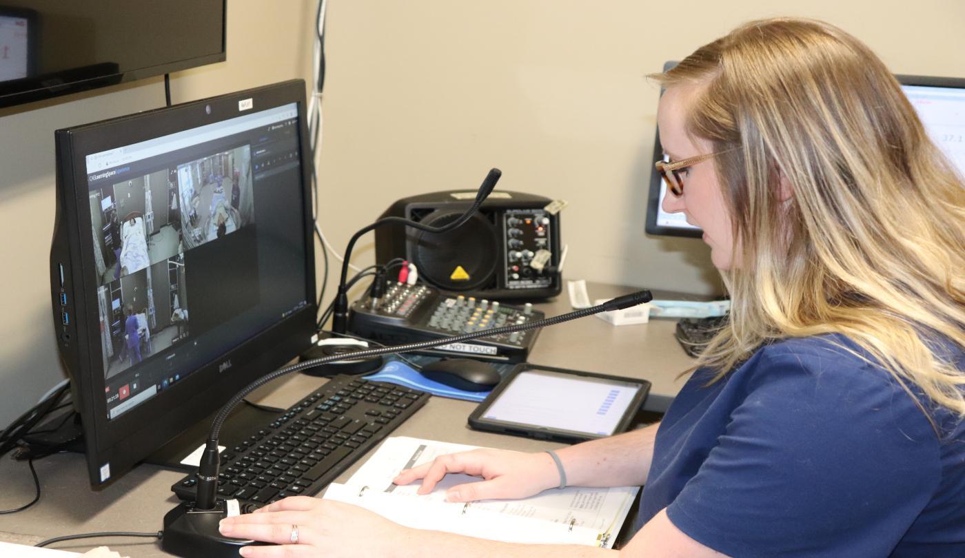 An instructor monitors a clinical simulation from the control room while voicing the patient. ABSN-NUR-3251
