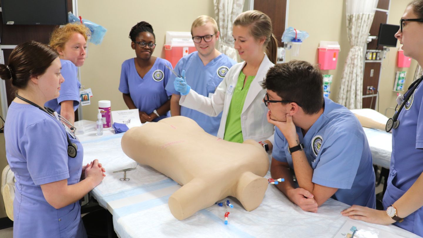 Dr. Elmore demonstrating suturing techniques to students at a collaborative table. 