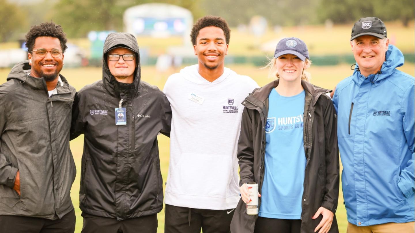 three people smile together on a field