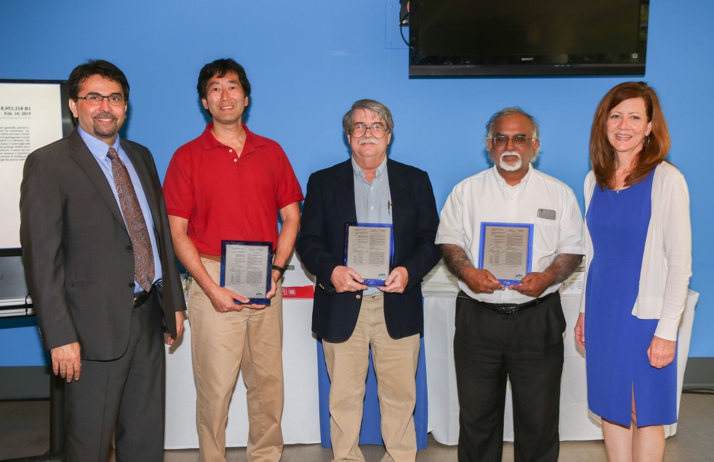 OTC Director Kannan Grant and Research Program Coordinator Becky England standing with three inventors holding patent awards