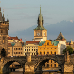 Old Town Bridge Tower and St. Francis of Assisi Church rising over Charles Bridge at golden hour