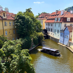 A boat cruises the Čertovka canal past Kampa's colorful houses