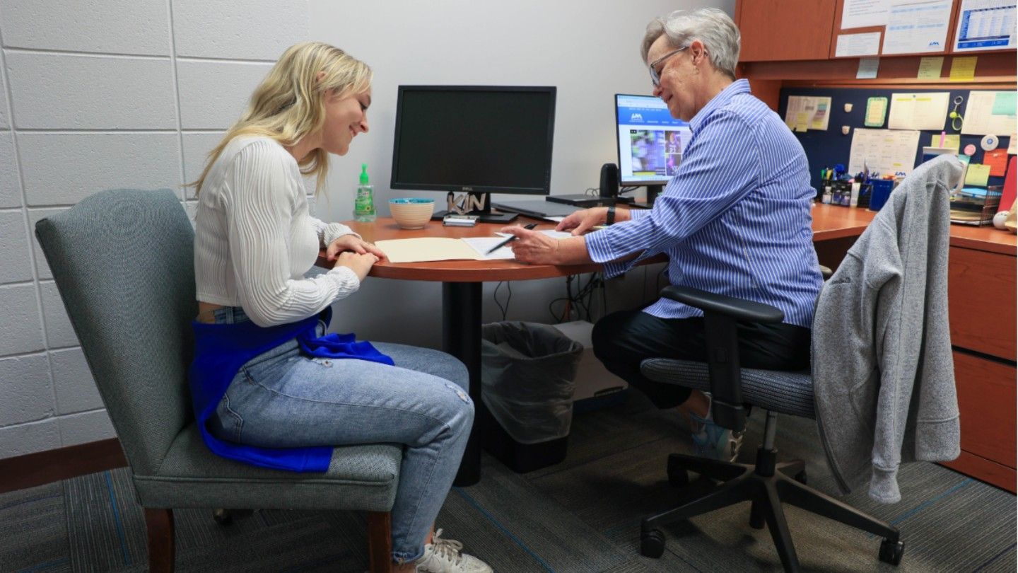 two people work on paperwork together at a desk