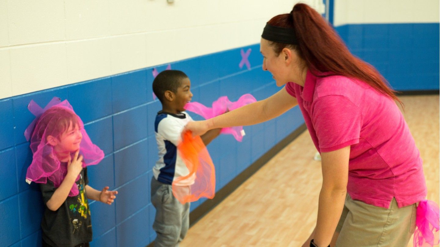 children play with scarfs alongside adult