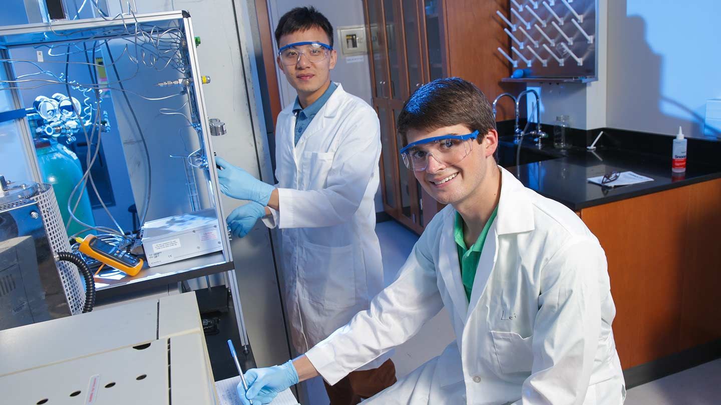 two young men use lab equipment