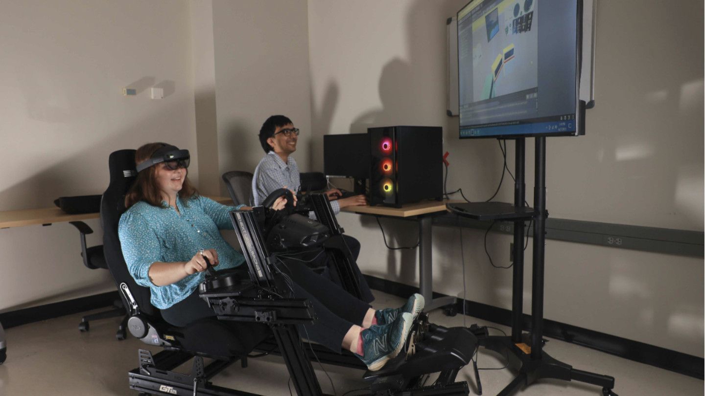 a woman uses immersive technology while a man watches a monitor