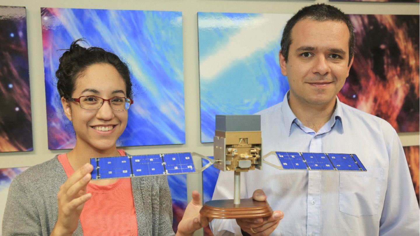 a man and woman hold a model satellite