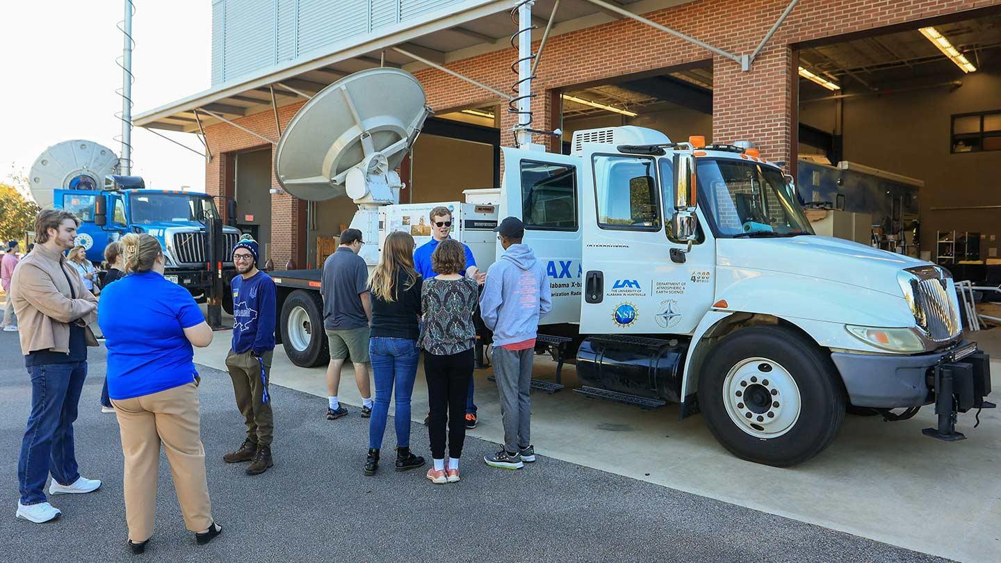 a group stands before weather equipment in a parking lot