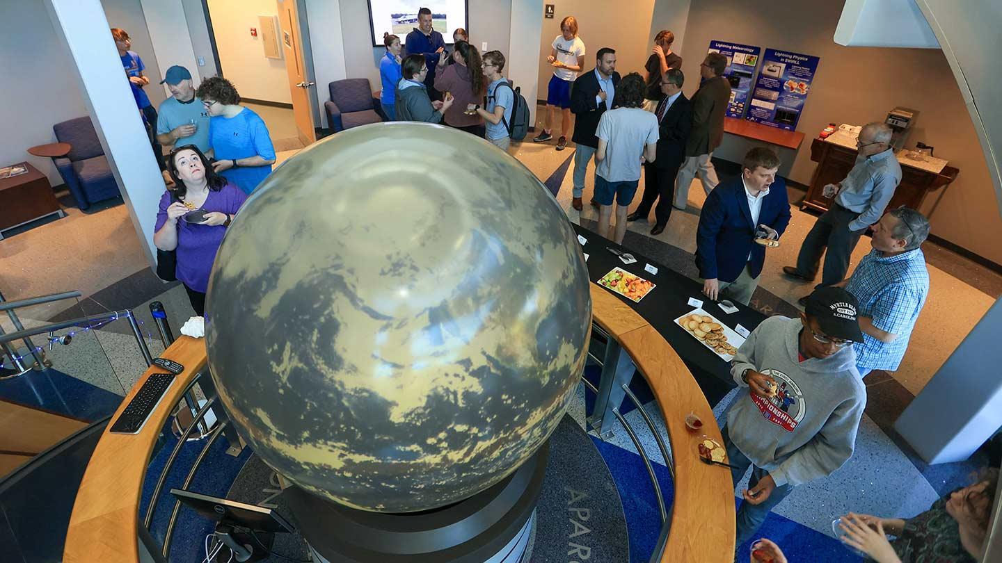 A large group enjoy food and the sight of a large weather globe