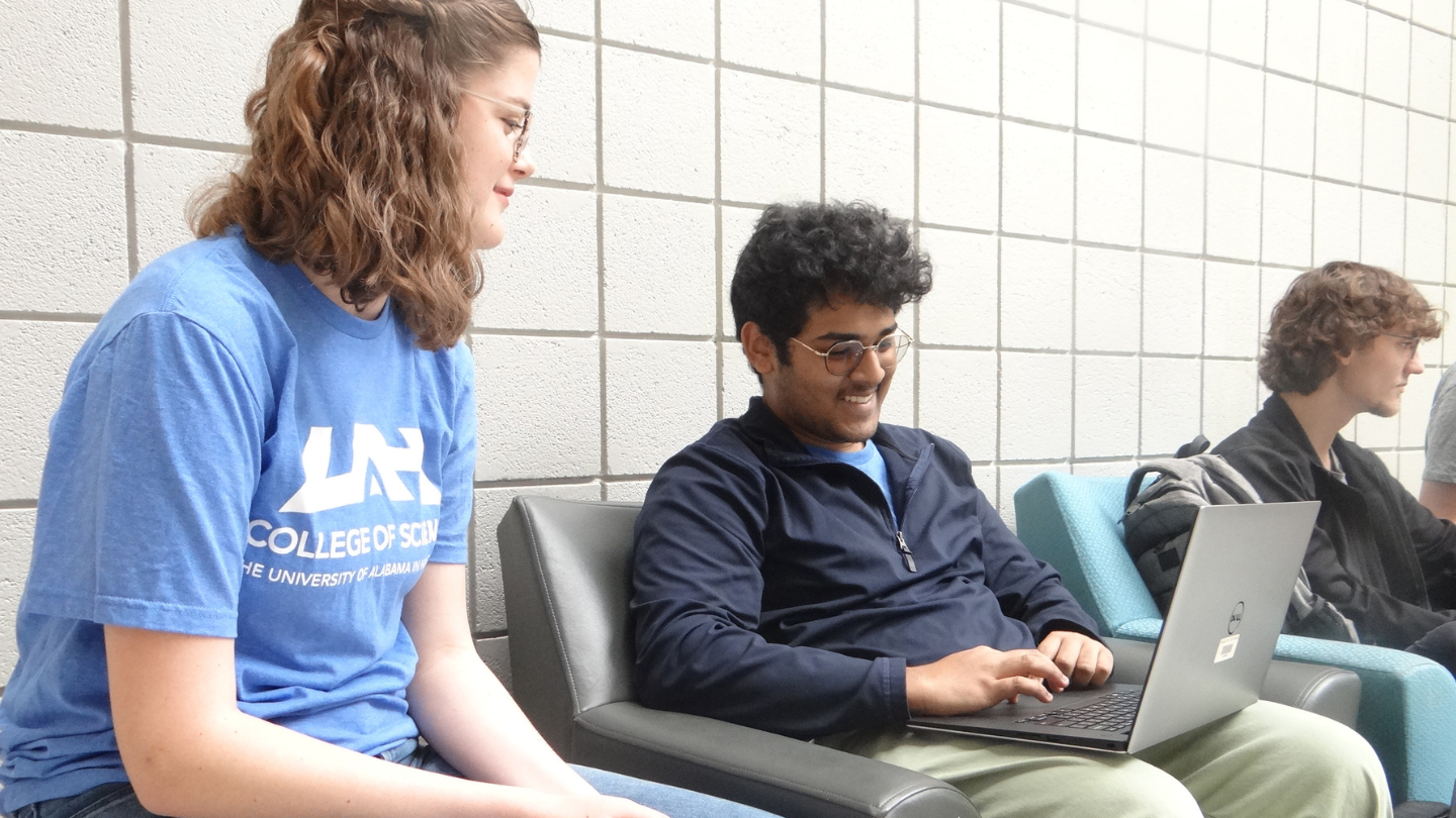 UAH Computer Science students collaborate on a laptop in a campus study area.