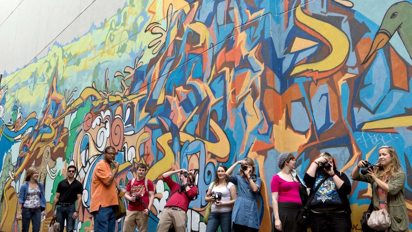 students pose in front of a graffiti wall