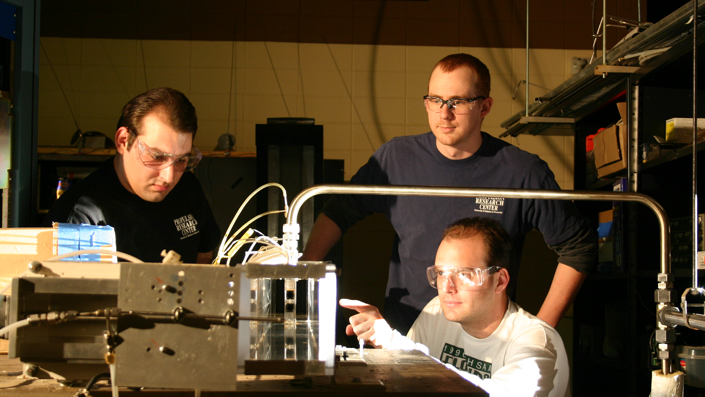 three men use large technical equipment