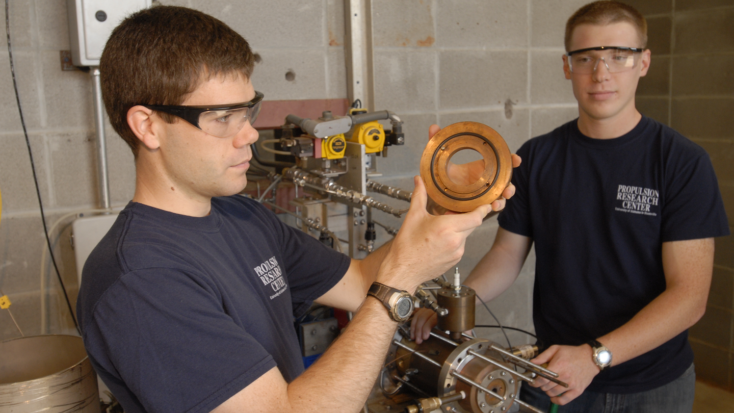two students examine an apparatus