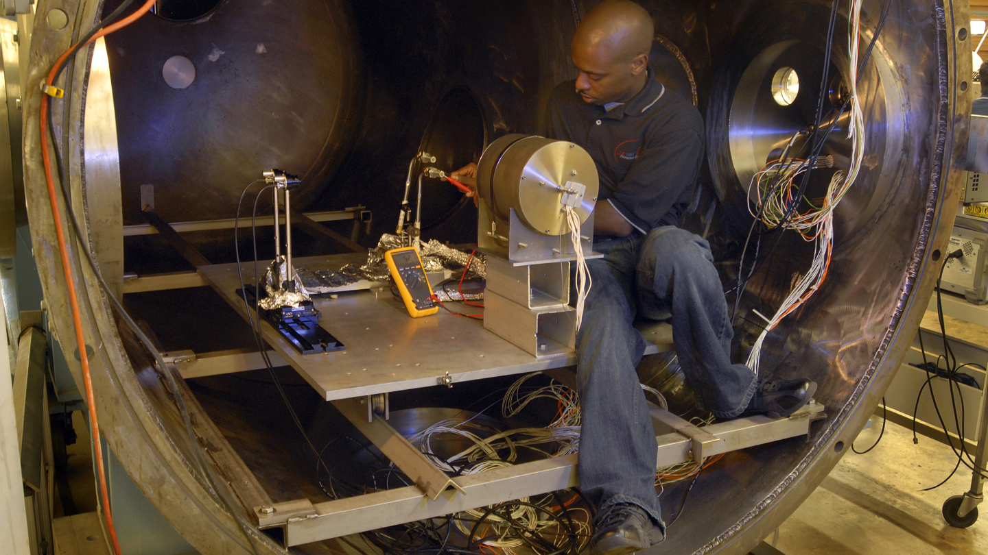 a man makes adjustments to a vacuum chamber